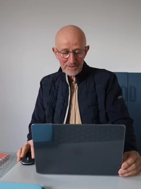 Un dirigeant heureux derrière son ordinateur, cherchant des solutions pour performer dans le pilotage de son entreprise.