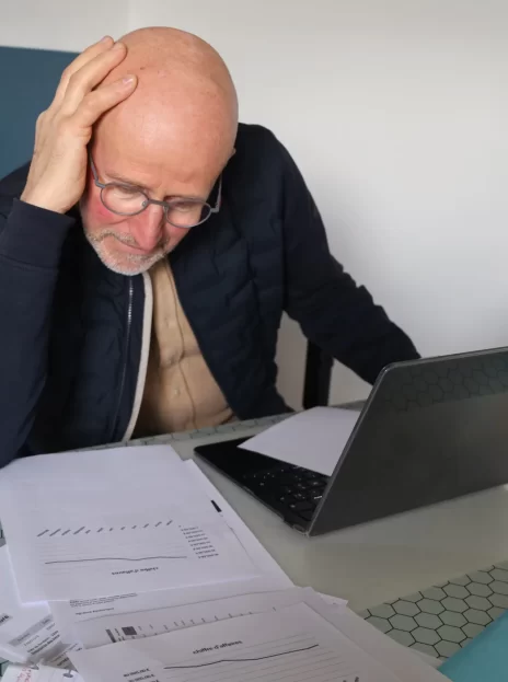 Un dirigeant obnubilé par ses chiffres dans son bureau avec sa main qui tient sa tête, l'air pensif
